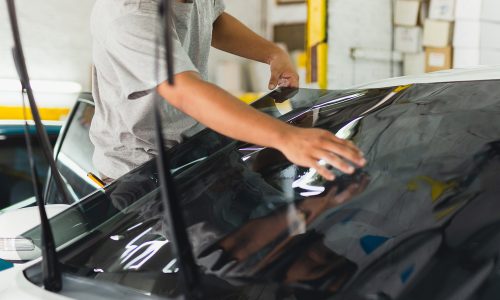 Car specialist applying tinting foil on a car window in auto service