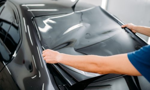 Male specialist with car tinting film in hands Male specialist with car tinting film in hands. Installation process, tinted auto glass installing procedure
